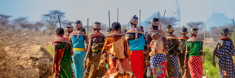 people in orange and yellow traditional dress walking on brown sand during daytime